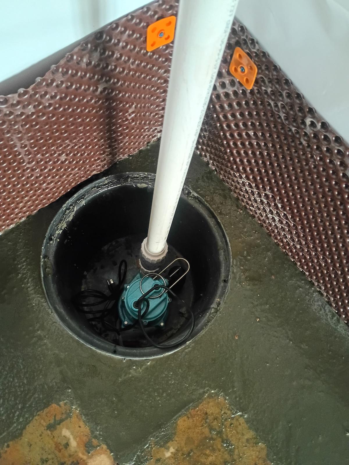 Basement Medic technician installing a new sump pump in a freshly cut sump pit
